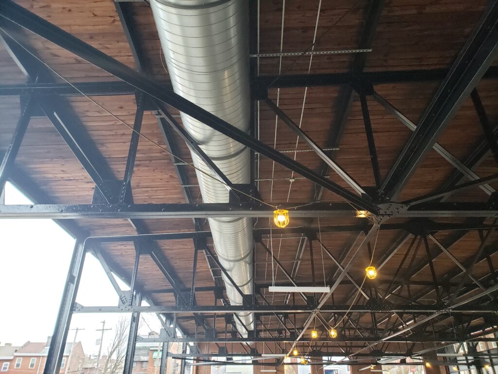 The industrial ceiling of Mintwood with black piping and aluminun venting.