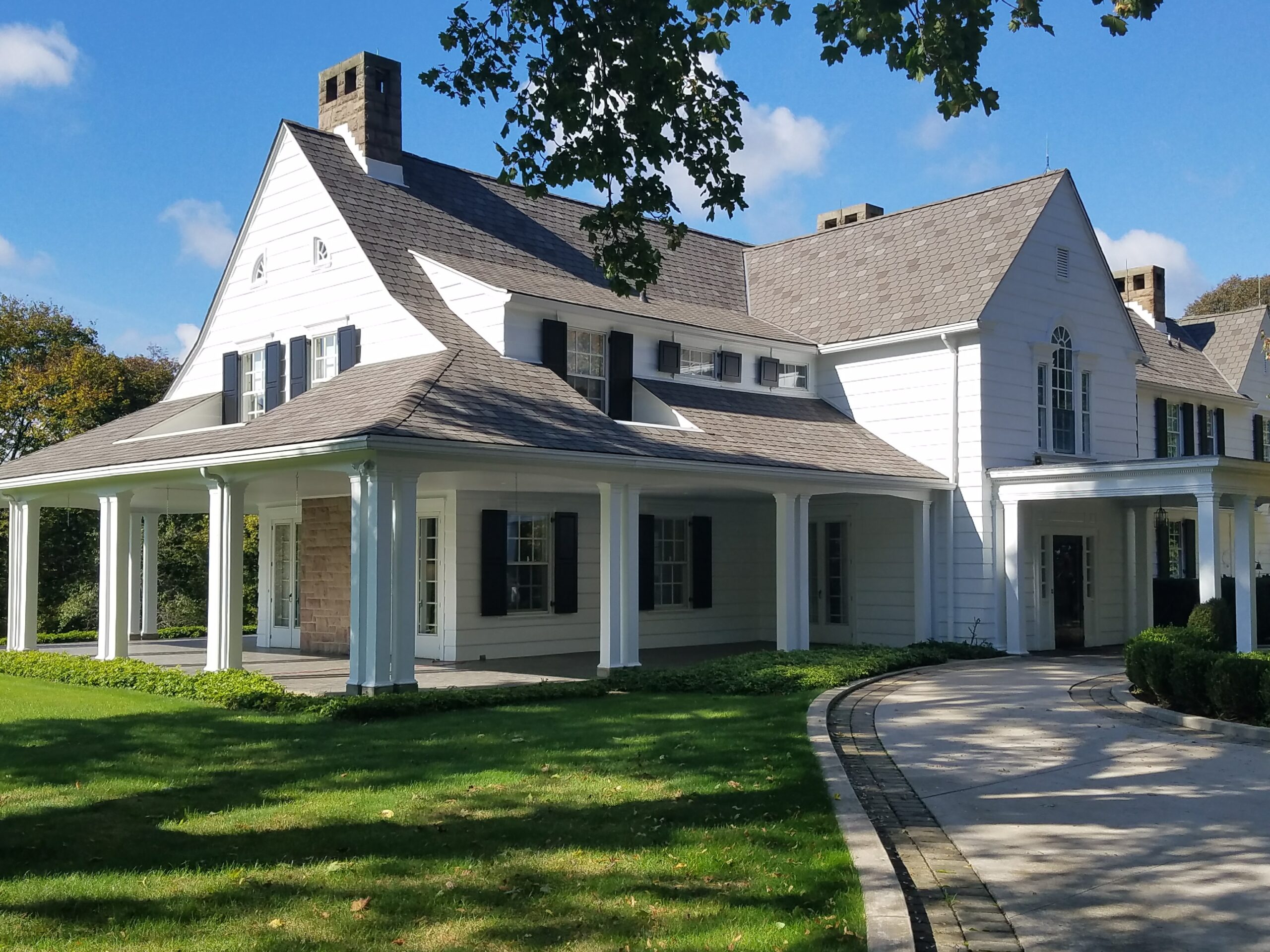 The Exterior of. freshly painted White Home with a driveway and grass lawn.