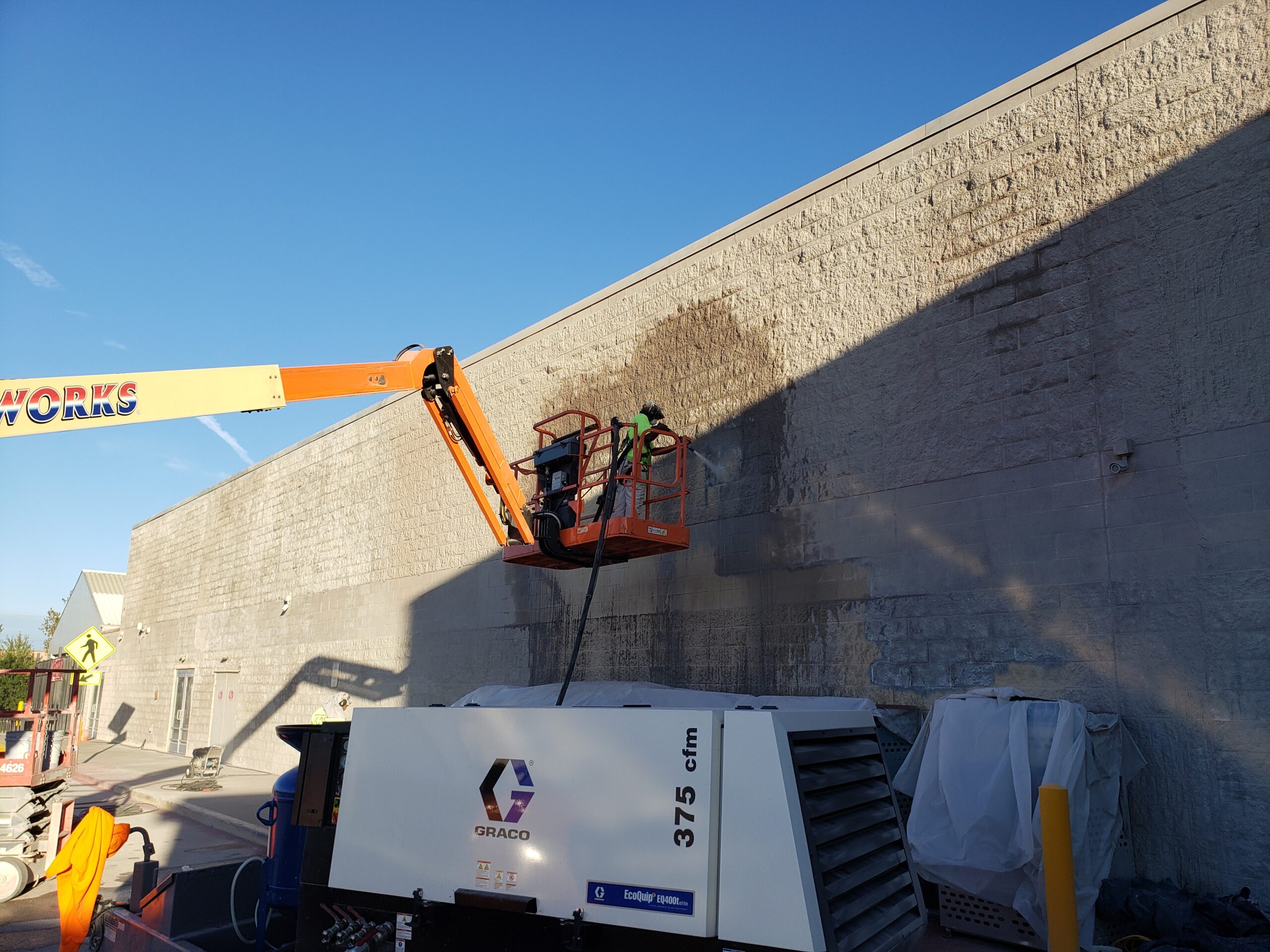 A Man on a Lift Vapor Blasting the Exterior of a Commercial Building.