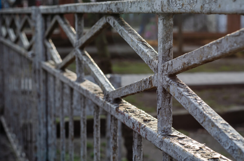 A close-up of an old, dirty, metal railing.